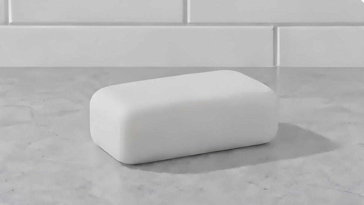A plain white bar of soap on a marble counter