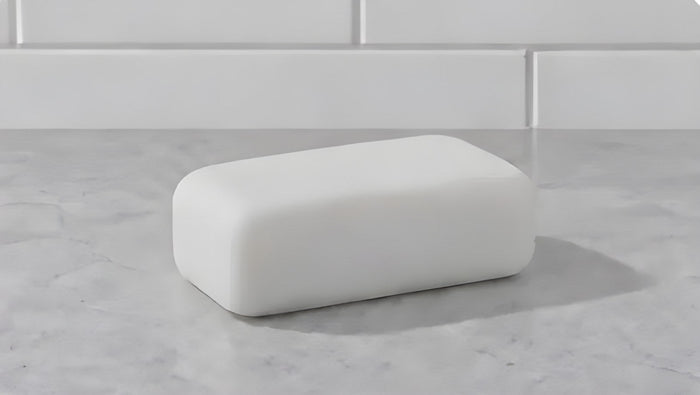 A plain white bar of soap on a marble counter