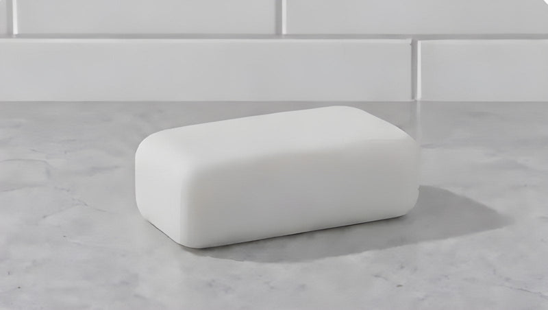A plain white bar of soap on a marble counter