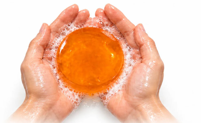 Cupped hands holding a lathered persimmon soap bar
