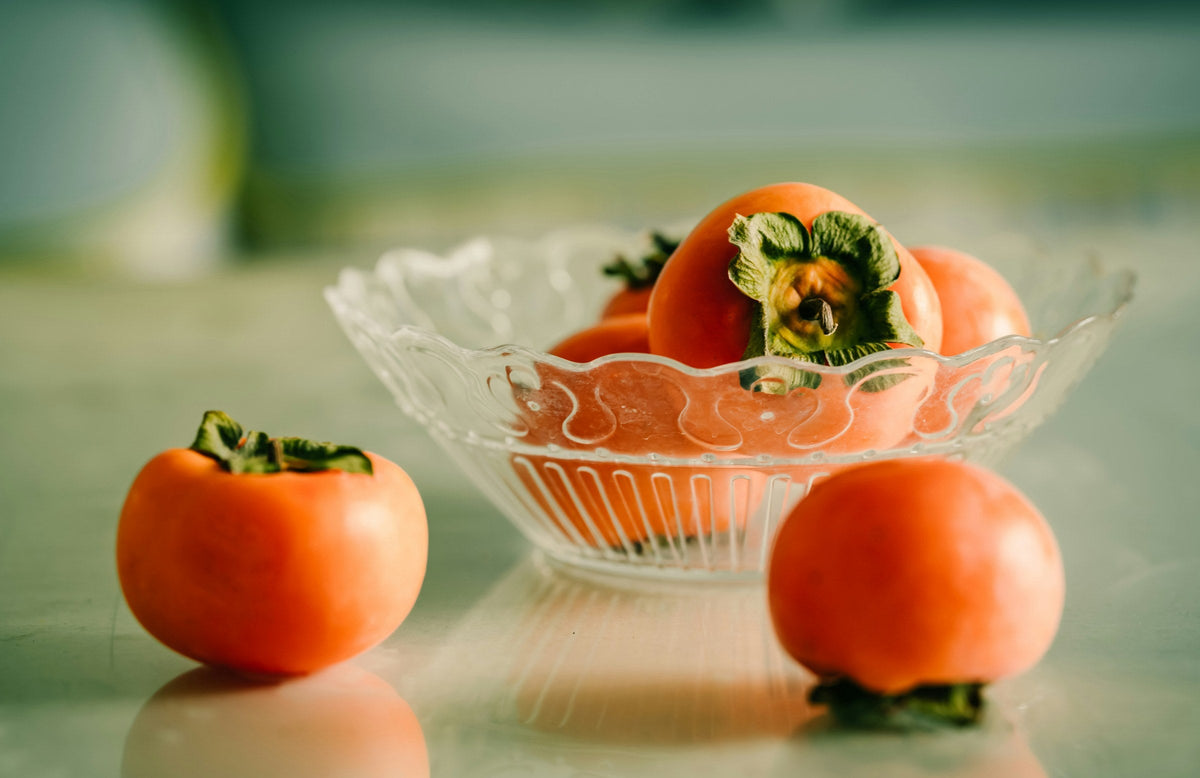 Fresh persimmons in a glass bowl